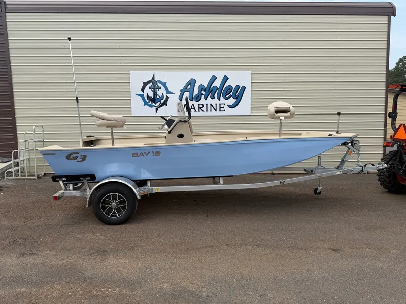 The Image of A G3 Bay 18 BAY-90SHO boat on a trailer in front of a building with an Ashley Marine sign. - 1