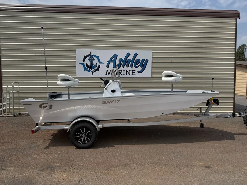 The Image of A white G3 Bay 17 boat on a trailer in front of a building with "Ashley Marine" sign. - 1
