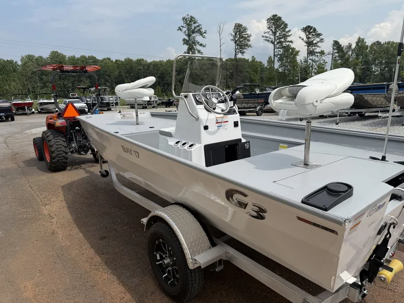 Slide: The Image of A white 2027 G3 Bay 17 boat on a trailer, surrounded by trees. - 7