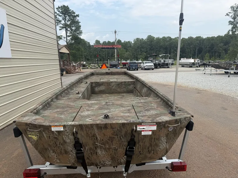 Slide: The Image of A rugged camo-patterned boat on a trailer, surrounded by trees and vehicles. - 4