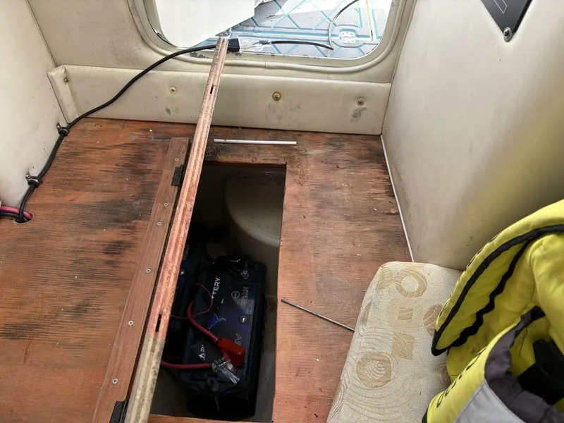 Slide: The Image of An open floor area in a boat reveals a battery and cables. A yellow life jacket is nearby. - 35