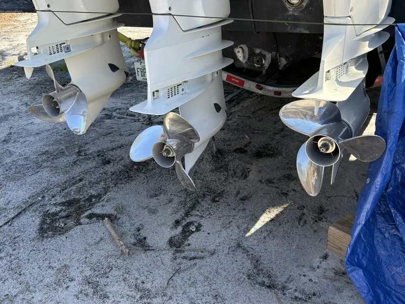 Slide: The Image of Three outboard motors with shiny propellers are positioned on a sandy ground. - 5