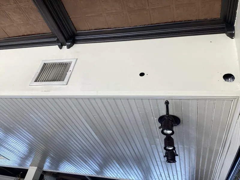 Slide: The Image of The ceiling features white wood paneling with black light fixtures and a vent. - 32