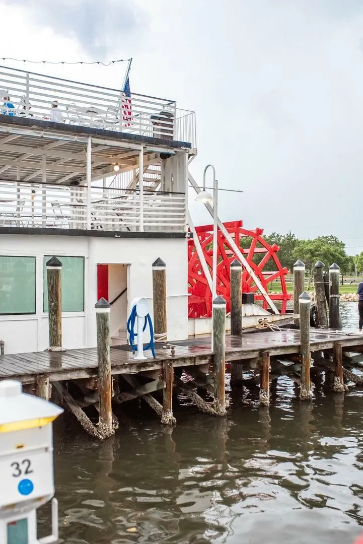 Slide: The Image of A two-story boat with a red paddle wheel docked at a wooden pier. - 14