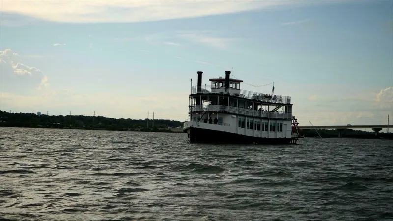 Slide: The Image of A historic paddle wheel boat cruises on calm waters, surrounded by a scenic landscape. - 6