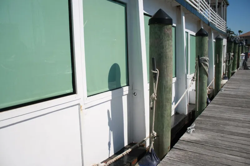 Slide: The Image of A white boat with green windows is moored at a wooden dock. - 16