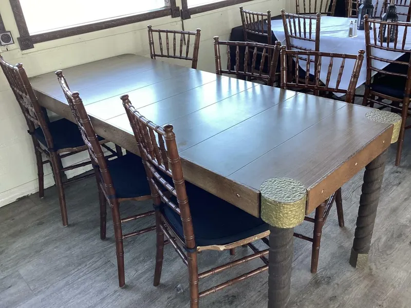 Slide: The Image of A long wooden table with dark chairs is set in a room with wooden flooring. - 37