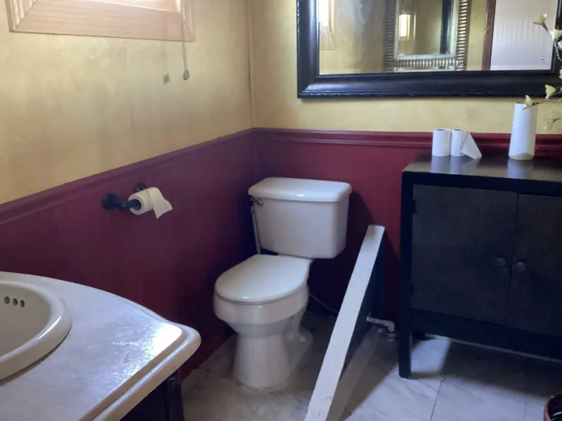 Slide: The Image of A bathroom with a toilet, sink, and mirror. The walls are yellow and red. - 47