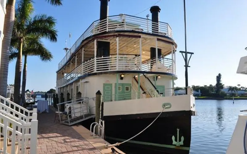Slide: The Image of A two-story paddle wheel boat docked at a sunny pier, surrounded by palm trees. - 4