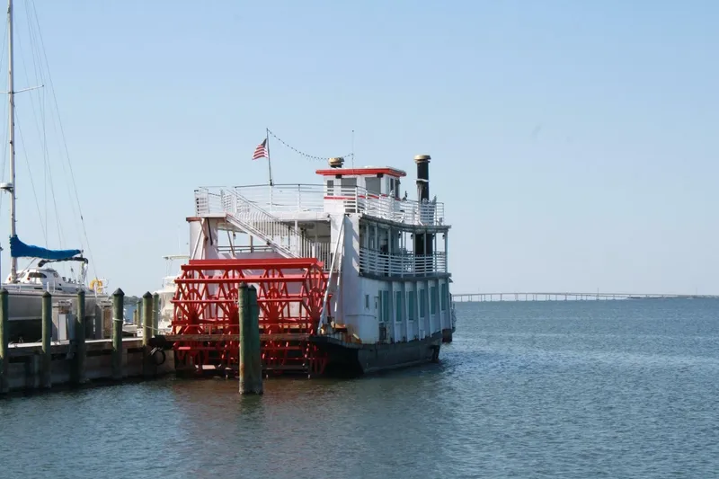 Slide: The Image of A white paddle wheel boat with a red wheel docked. An American flag flies on top. - 5