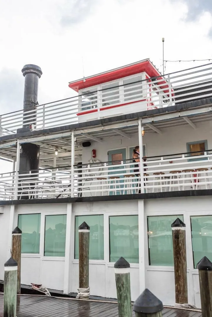 Slide: The Image of A two-story paddle wheel boat with a red roof and smokestack, docked at a pier. - 9