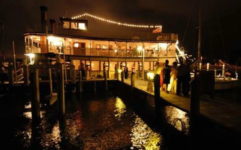 Slide: The Image of A lit-up two-deck boat docked at night, surrounded by people. - 7