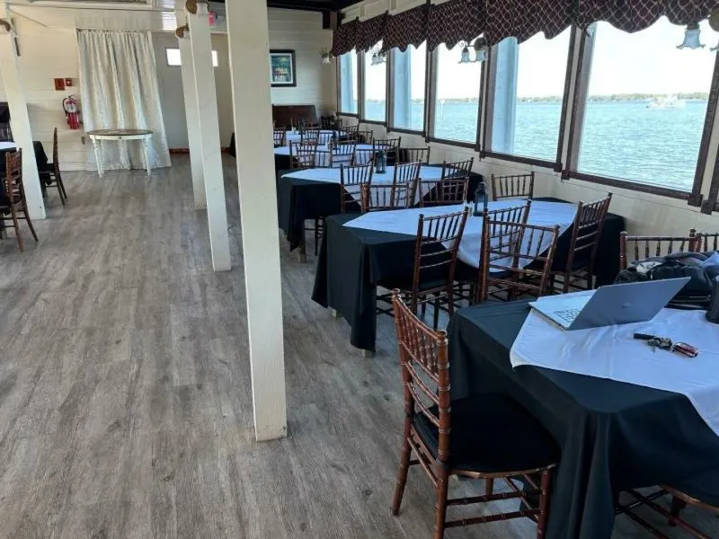 Slide: The Image of A spacious interior with wooden flooring and covered tables, surrounded by large windows overlooking the water. - 40