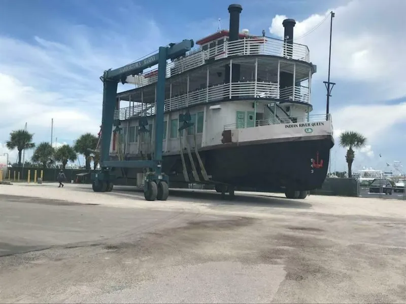 Slide: The Image of A large paddle wheel boat is being lifted on land by a crane. - 3