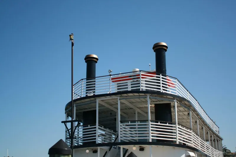 Slide: The Image of A two-story paddle wheel boat with white railings and two black smokestacks. - 12