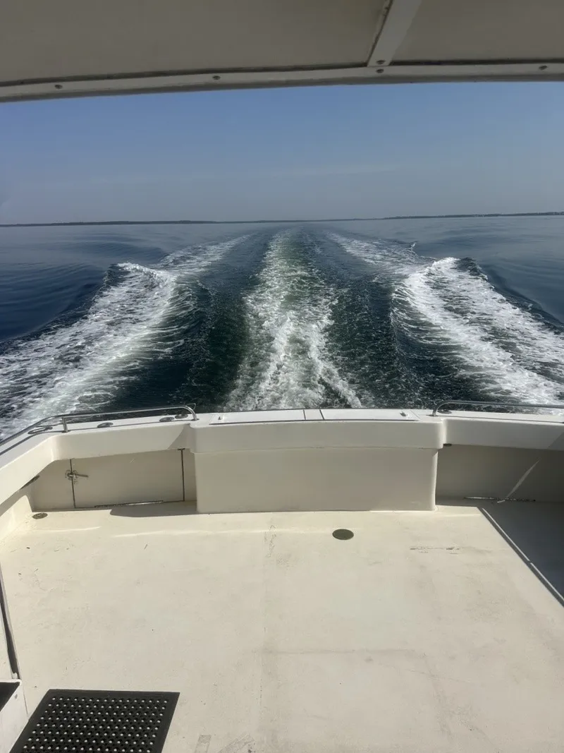 Slide: The Image of The stern of a boat shows a wide wake on calm water under a clear sky. - 4