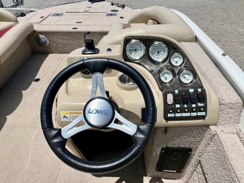 Slide: The Image of The image shows the helm of a 2016 Lowe Sport Deck 224 boat with a steering wheel and gauges. - 39