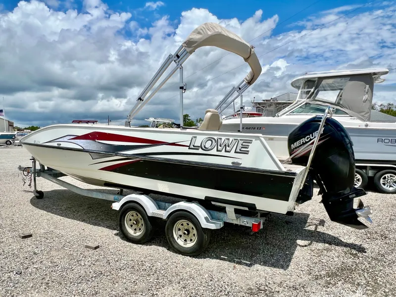 Slide: The Image of A 2016 Lowe Sport Deck 224 on a trailer, featuring an outboard motor and bimini top. - 7