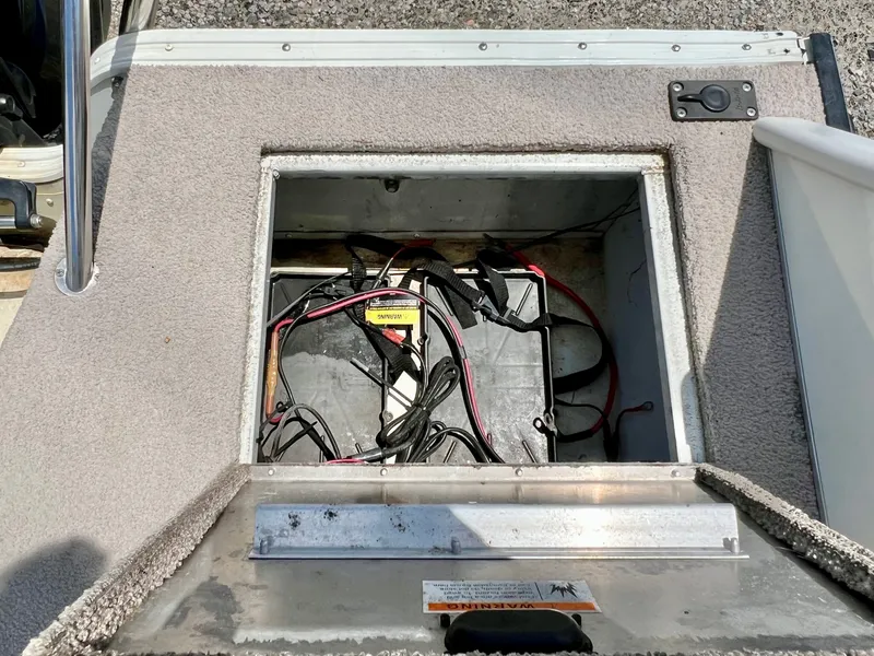 Slide: The Image of An open compartment on a boat reveals batteries and cables. The floor is carpeted. - 15