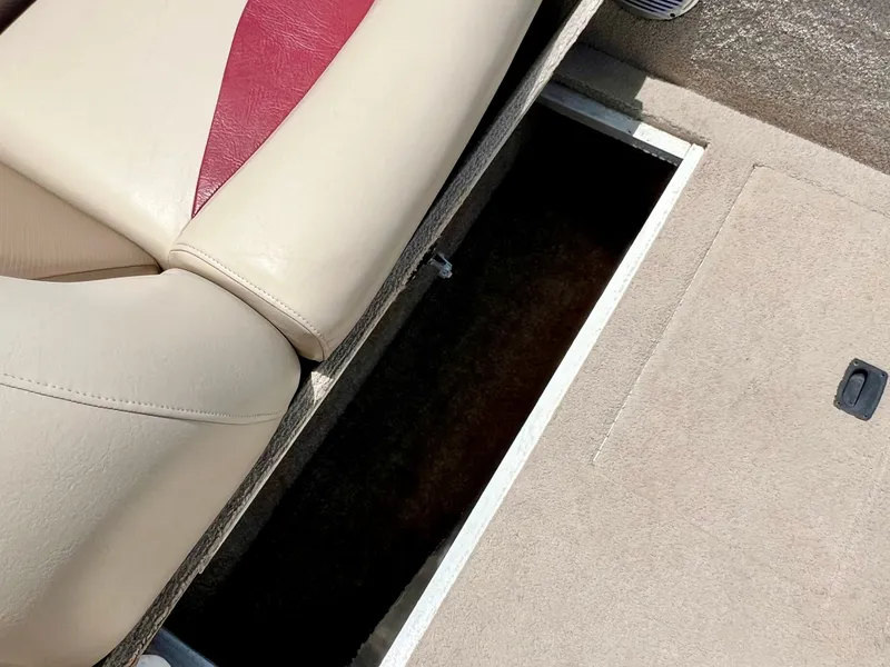 Slide: The Image of An open storage compartment on a boat with beige carpeting and a seat with a red accent. - 31