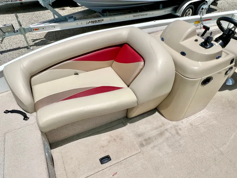 Slide: The Image of The image shows the cockpit of a 2016 Lowe Sport Deck 224 with beige and red seating. - 27