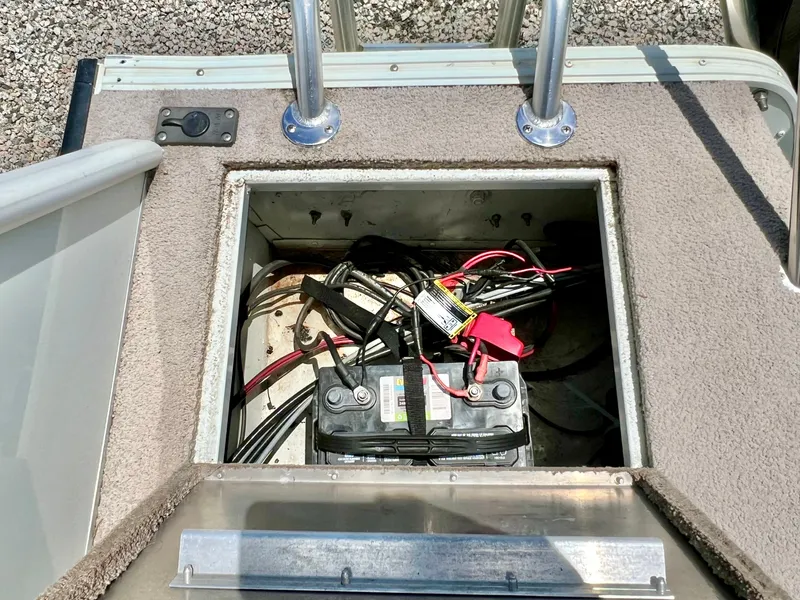 Slide: The Image of An open battery compartment on a boat with cables and a battery. - 16