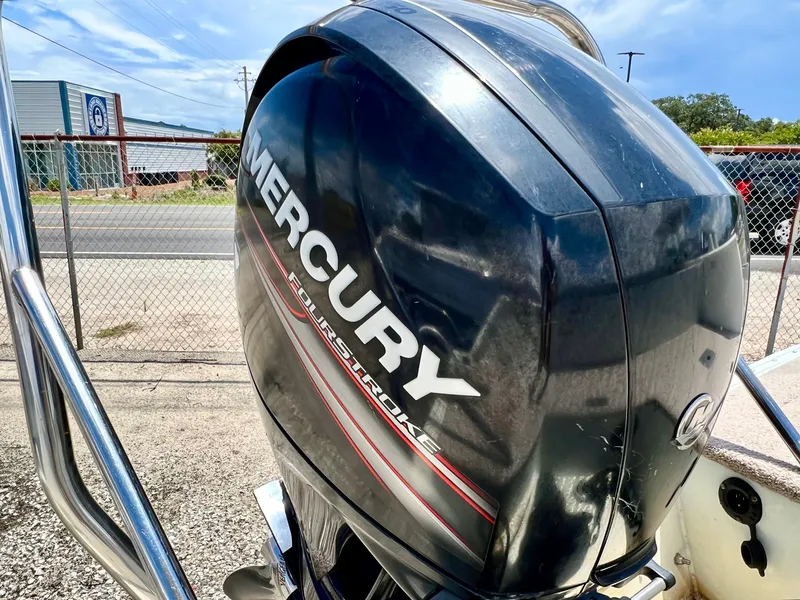 Slide: The Image of A Mercury FourStroke outboard motor is mounted on a boat, with a fence and buildings in the background. - 44