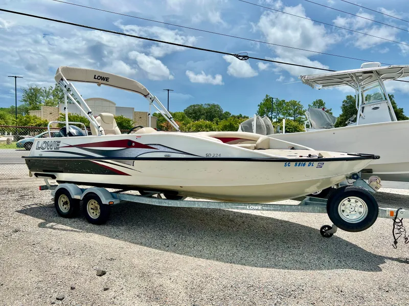 Slide: The Image of A white 2016 Lowe Sport Deck 224 boat on a trailer in a parking lot. - 1