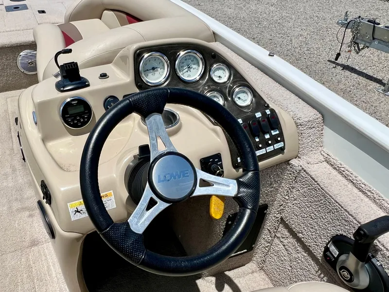 Slide: The Image of The image shows the helm of a 2016 Lowe Sport Deck 224 boat with various instruments. - 40