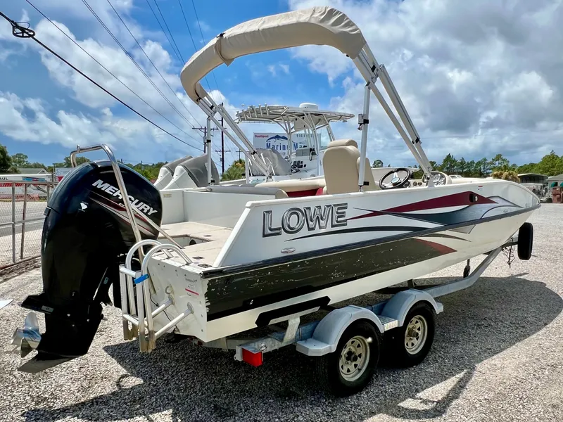 Slide: The Image of A 2016 Lowe Sport Deck 224 on a trailer, featuring a Mercury outboard motor and a Bimini top. - 3