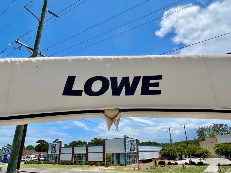 Slide: The Image of A part of a boat with the "LOWE" logo is visible. Buildings and a blue sky are in the background. - 47