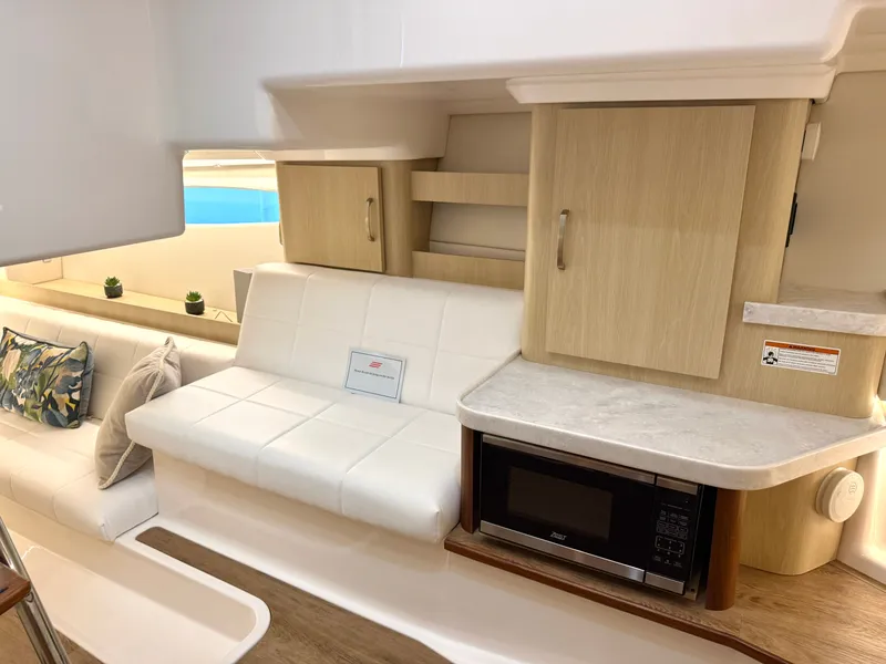 Slide: The Image of Interior of a 2023 Regal 36 XO with white sofa, microwave, and wooden cabinets. - 34