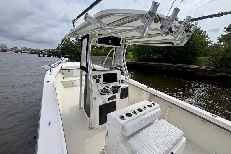 Slide: The Image of 2009 May-Craft 2700CCX boat on a calm river, featuring a central console and fishing rod holders. - 8