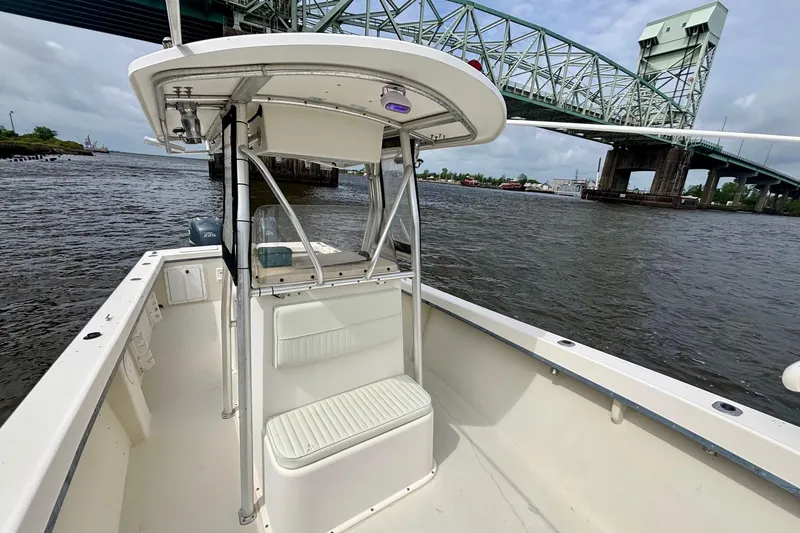 Slide: The Image of 2009 May-Craft 2700CCX boat on water near a bridge, showcasing spacious deck and seating. - 13