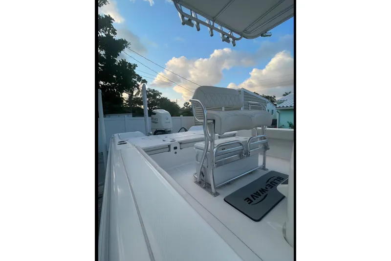 Slide: The Image of 2020 Blue Wave 2600 PureBay boat interior with seating and mat under a blue sky. - 7