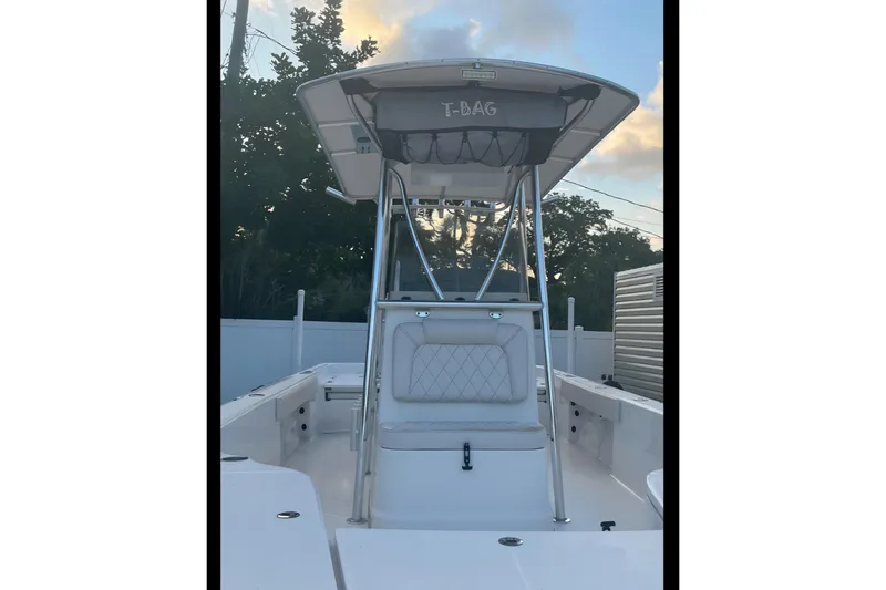 Slide: The Image of 2020 Blue Wave 2600 PureBay boat with T-top and seating, parked outdoors. - 5