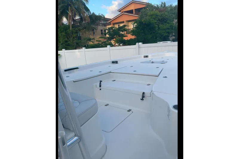 Slide: The Image of 2020 Blue Wave 2600 PureBay boat deck with seating, surrounded by trees and a fence. - 6