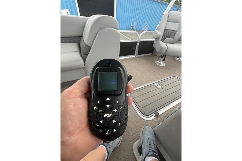 Slide: The Image of Hand holding a boat remote control on a 2021 Ranger Reata 223FC pontoon boat. - 19