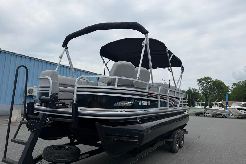 Slide: The Image of 2021 Ranger Reata 223FC pontoon boat with canopy on trailer, parked outdoors. - 2