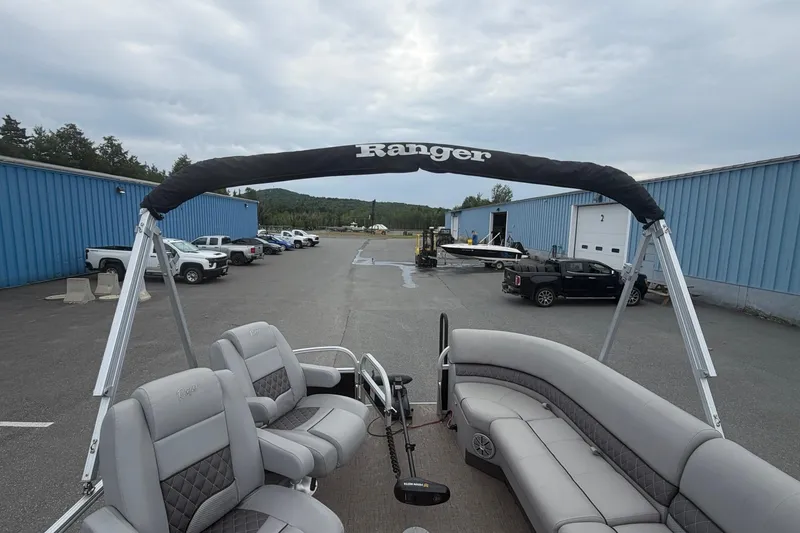 Slide: The Image of 2021 Ranger Reata 223FC pontoon boat with gray seating, parked near blue warehouses. - 3