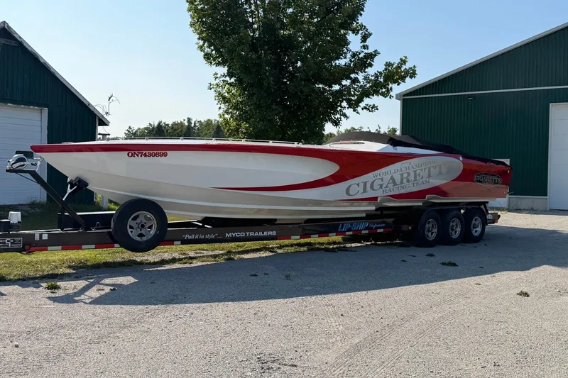 Slide: The Image of 2003 Cigarette 36' Gladiator speedboat on trailer, parked outdoors near green buildings. - 45