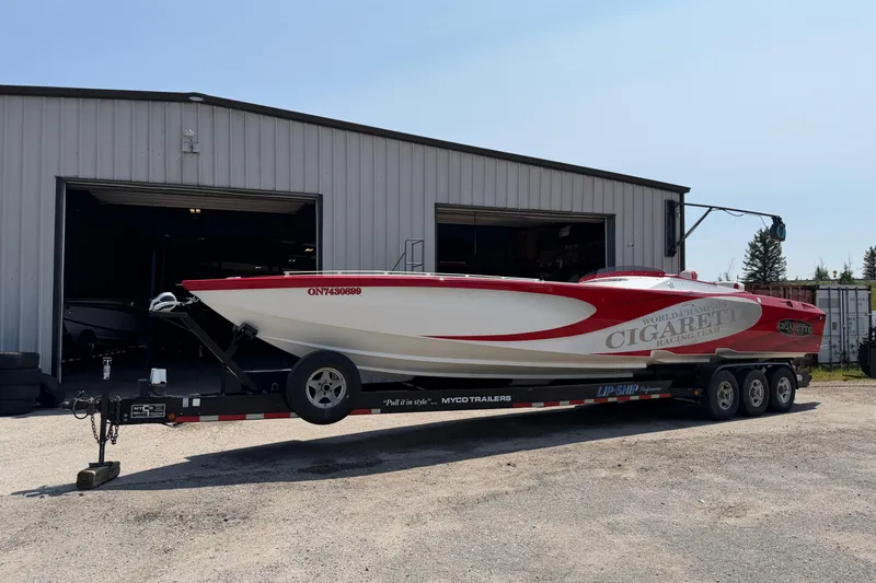 Slide: The Image of 2003 Cigarette 36' Gladiator boat on trailer outside a garage. - 16
