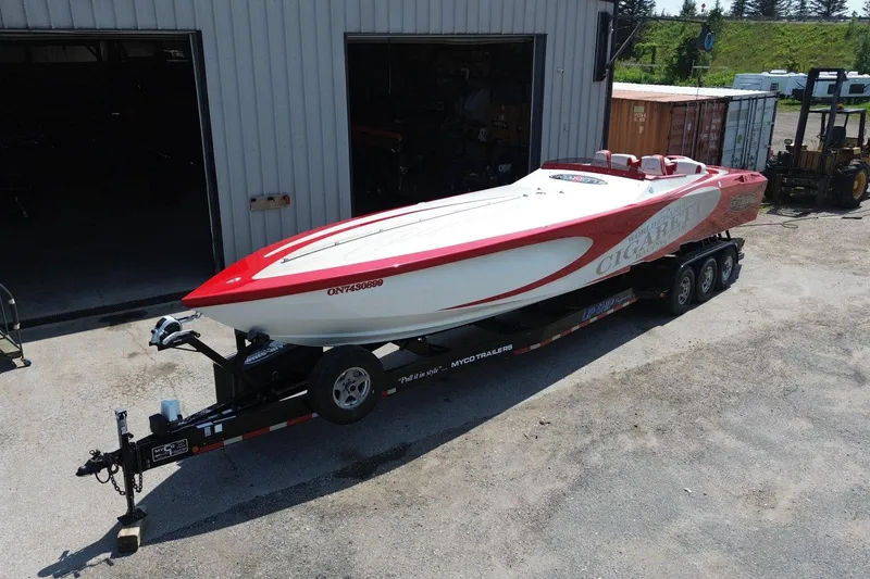 Slide: The Image of 2003 Cigarette 36' Gladiator speedboat on trailer, red and white design, parked outside a garage. - 3