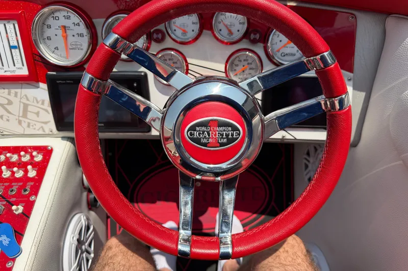 Slide: The Image of Red steering wheel of a 2003 Cigarette 36' Gladiator boat with gauges and controls. - 34