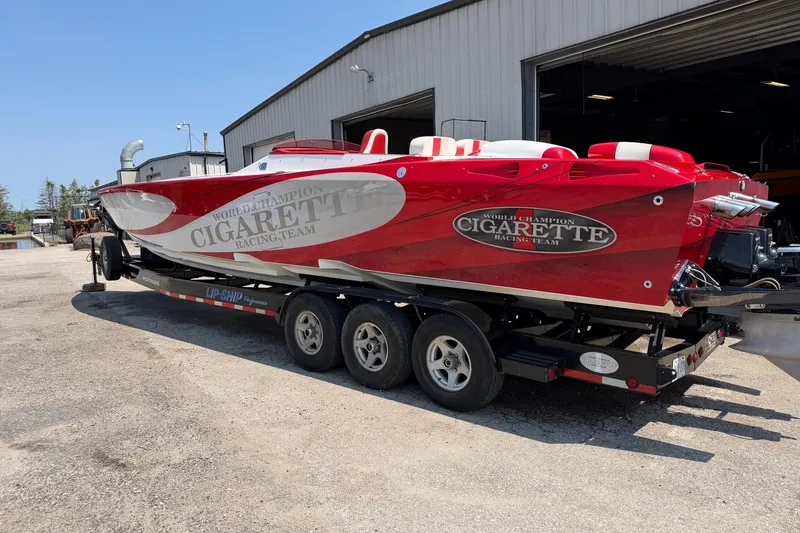 Slide: The Image of 2003 Cigarette 36' Gladiator boat on trailer, red and white, parked outside a garage. - 15