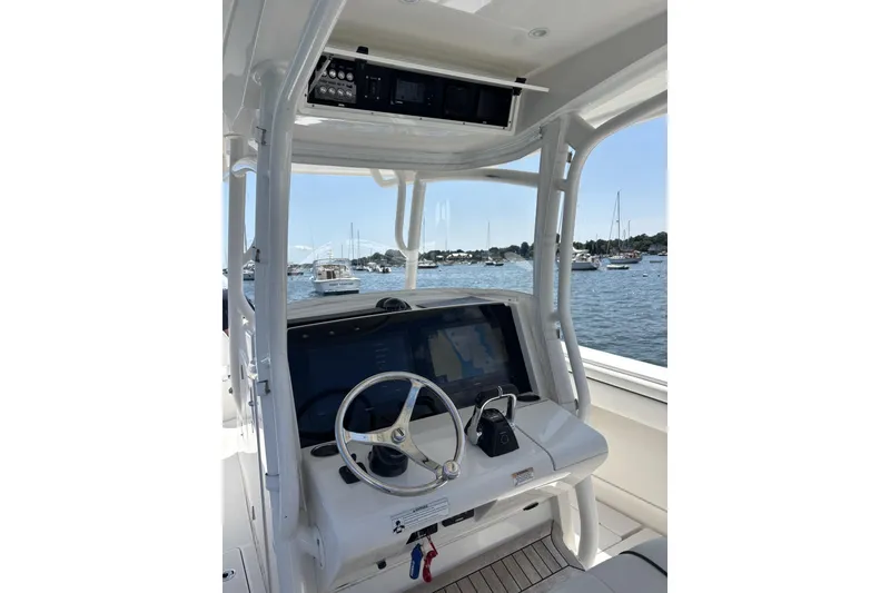 Slide: The Image of 2018 Jupiter 34 boat helm with steering wheel and navigation screen, overlooking marina. - 2
