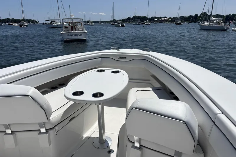 Slide: The Image of 2018 Jupiter 34 boat interior with seating and table, anchored in a scenic harbor. - 7
