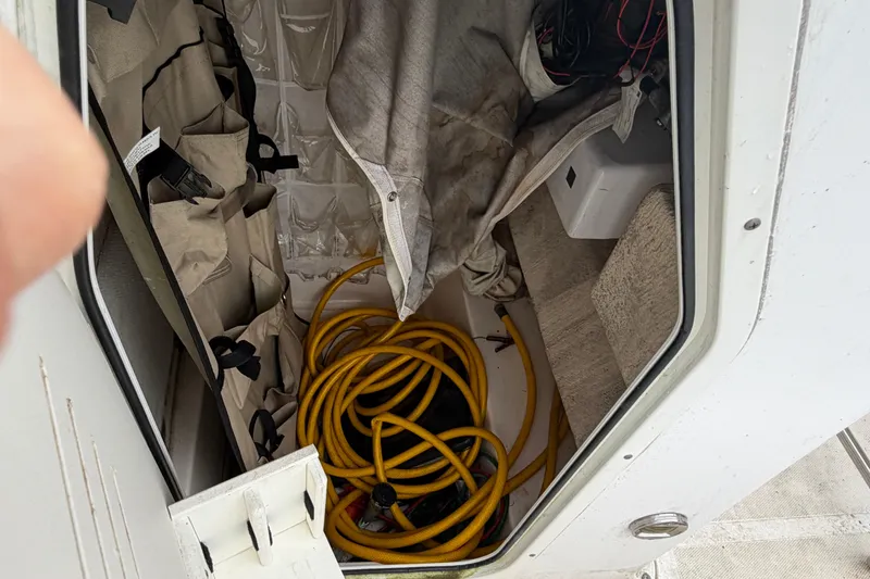 Slide: The Image of Storage compartment of a 2006 Seahunt 207 Triton boat with coiled yellow hose. - 11