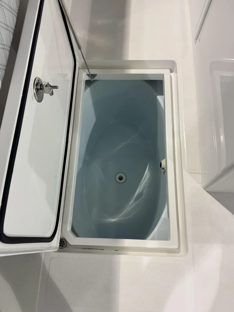 Slide: The Image of An open storage compartment on a boat with a blue interior and a drain. - 20