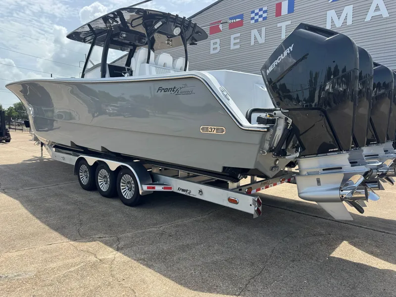 Slide: The Image of A gray Front Runner Boatworks 37 Cat boat from 2027 sits on a trailer. It has four outboard engines. - 2